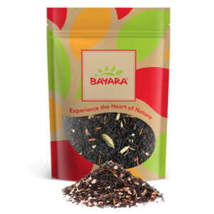 A 100g colorful pouch of Bayara Karak Power Tea showing spiced tea leaves and whole cardamom through a window.
