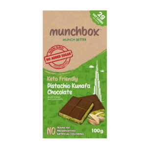A 100g Munchbox Keto Friendly Pistachio Kunafa Chocolate bar showing a green pistachio filling and "No Added Sugar" seal.