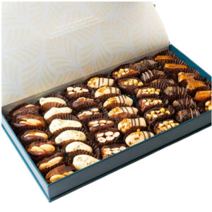 A large teal-colored gift box filled with rows of assorted gourmet dates, some coated in chocolate and others stuffed with nuts.