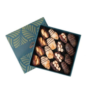 An open teal and gold gift box from Bayara featuring a variety of chocolate-coated and nut-stuffed gourmet dates.