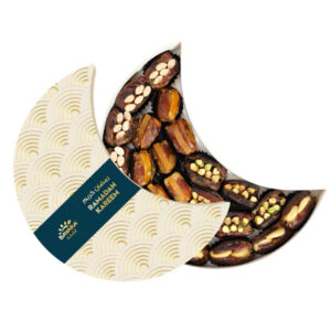 A white and gold moon-shaped Bayara Ramadan gift box filled with assorted nut-stuffed dates.
